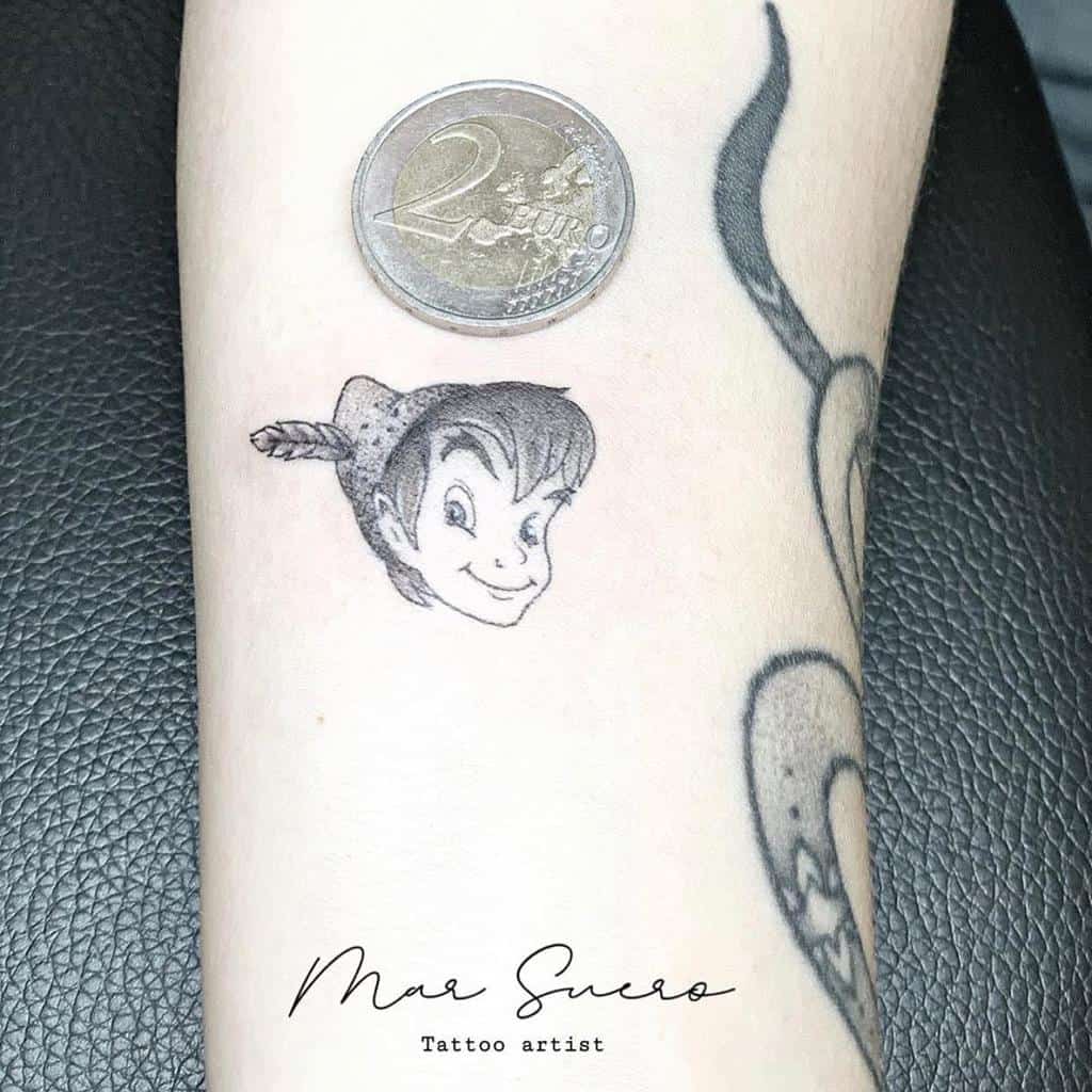 Small detailed Peter Pan portrait tattoo, showcasing his playful expression and feathered hat