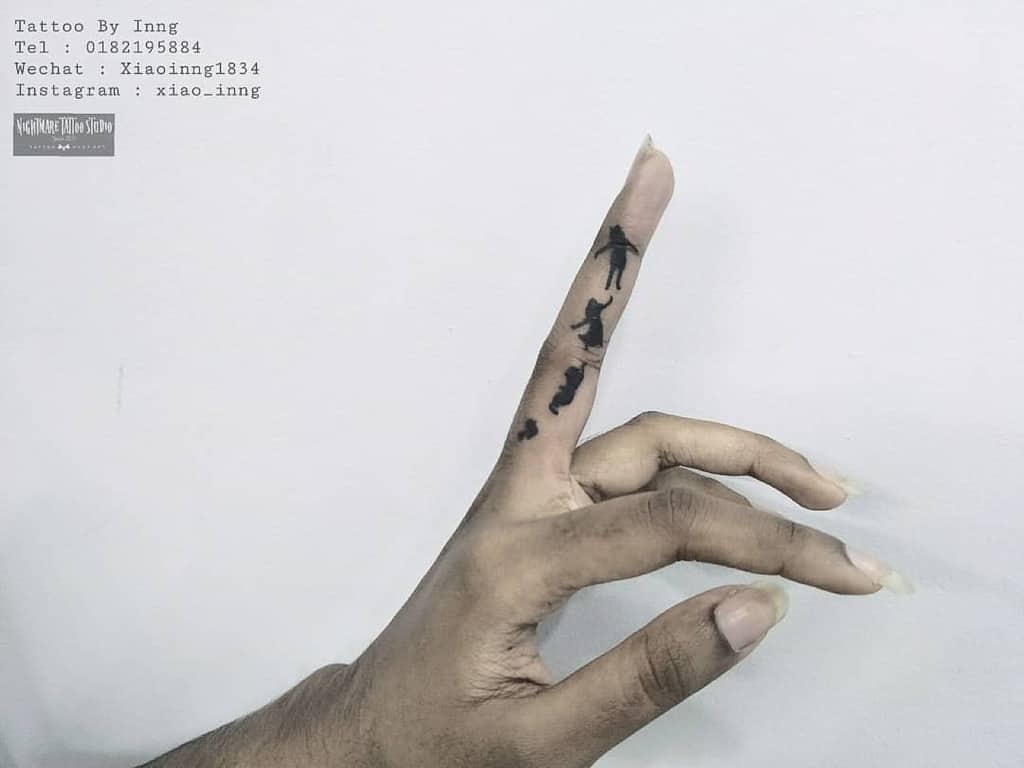 Small Peter Pan tattoo on finger featuring silhouettes of Peter, Wendy, and brothers flying, symbolizing adventure and imagination