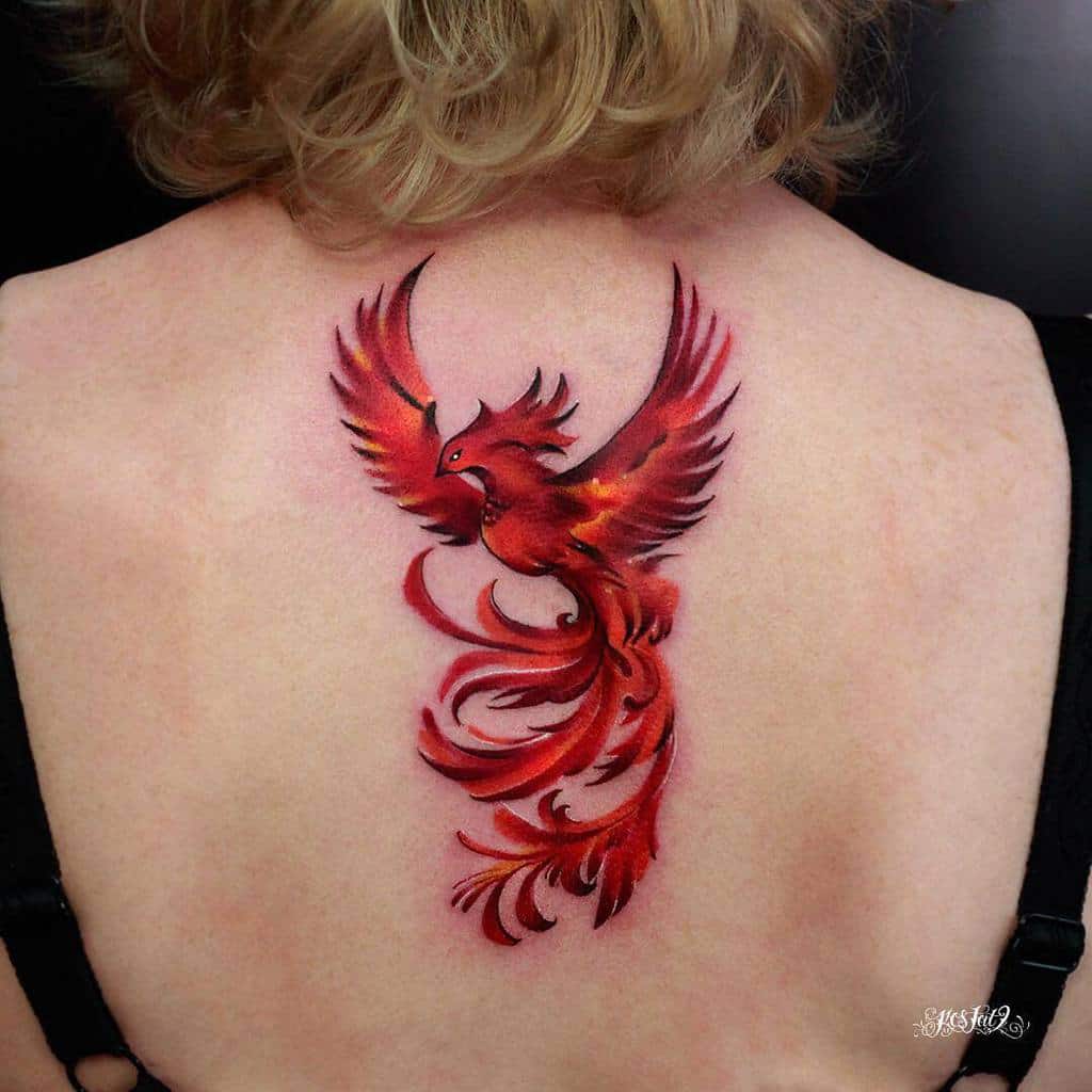 A vibrant red and orange phoenix tattoo on an upper back