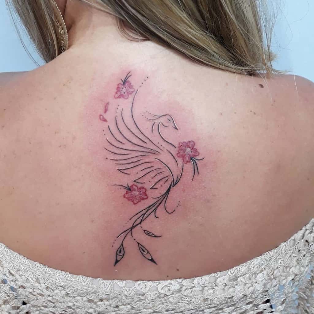 A stunning tattoo of a phoenix with pink flowers gracefully adorns a woman's back