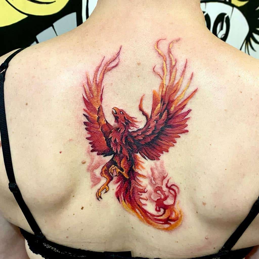 A stunning tattoo of a majestic phoenix with fiery red wings graces the woman's upper back