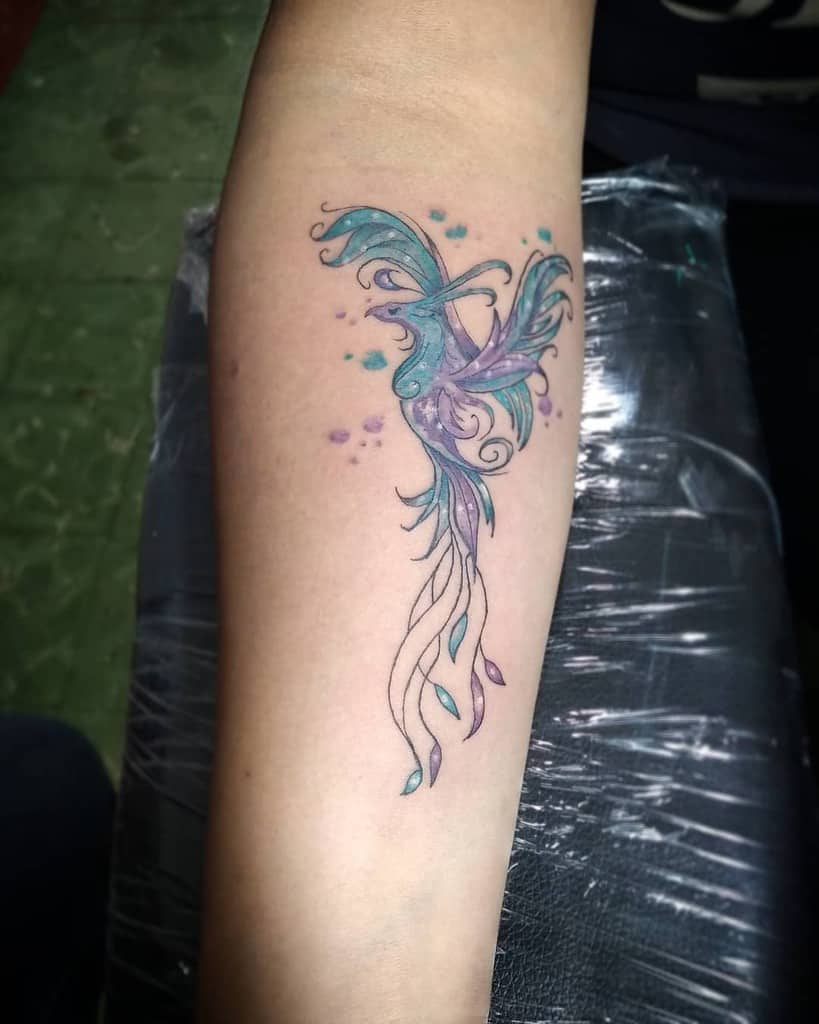 A vibrant abstract phoenix tattoo graces the forearm, its colors swirling in a dance of fiery elegance