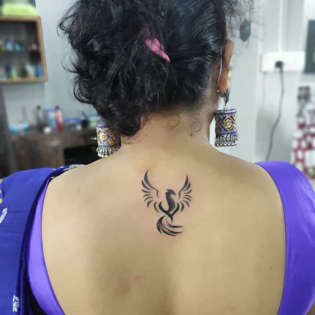 Small phoenix rising tattoo on the woman's back