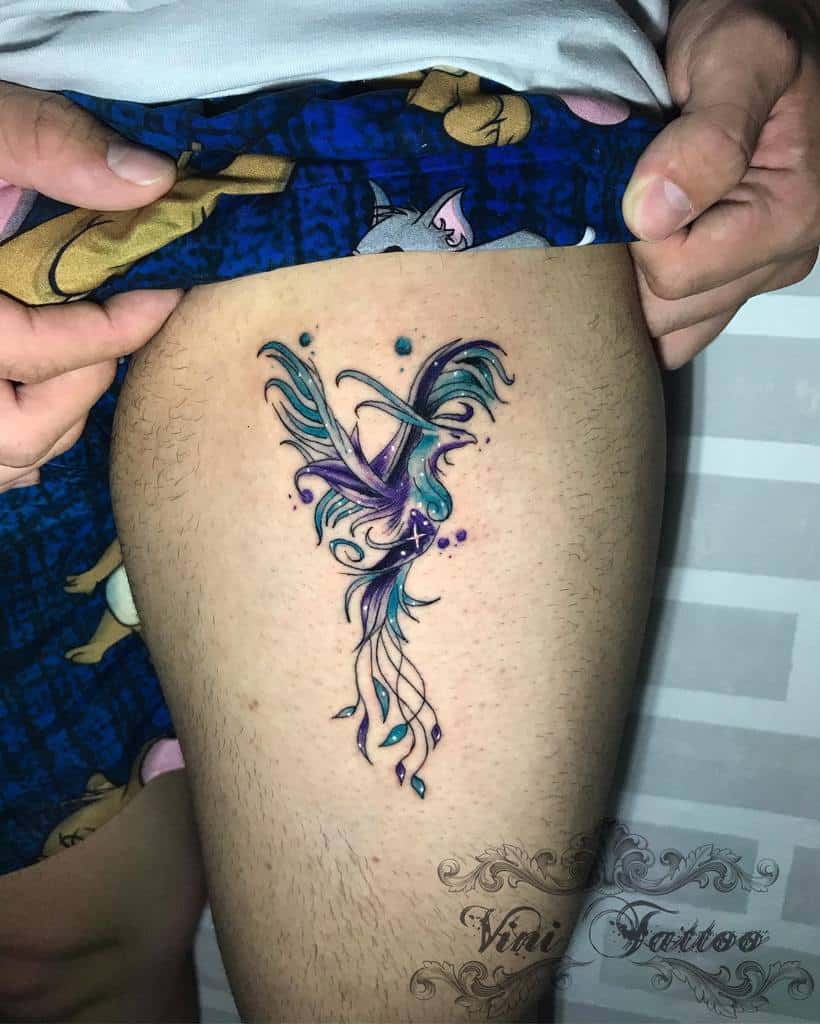Colorful phoenix tattoo on a man's upper thigh with floral and swirl designs