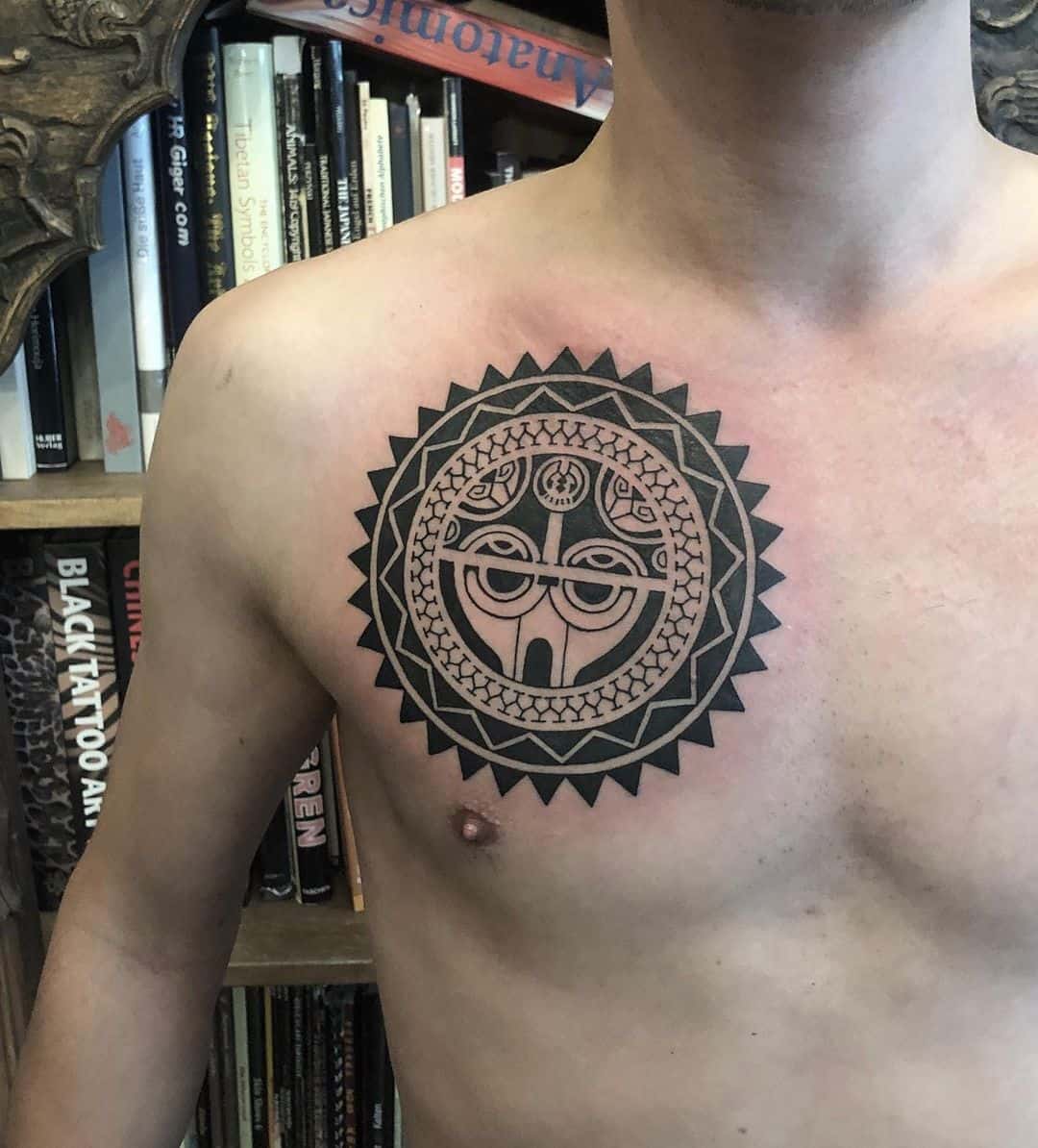 A large intricate geometric tattoo on their chest, featuring circular patterns and detailed line work