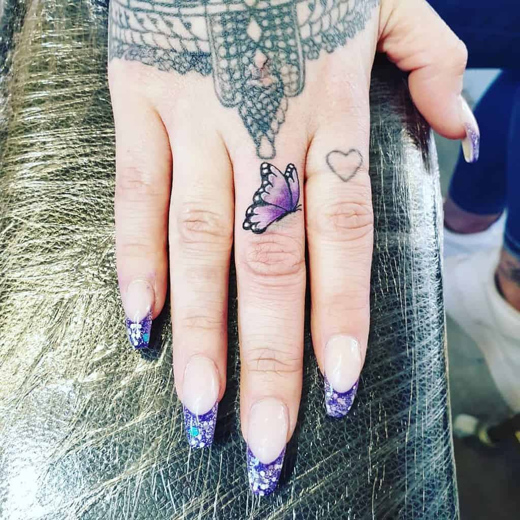 Small purple butterfly tattoo on the finger
