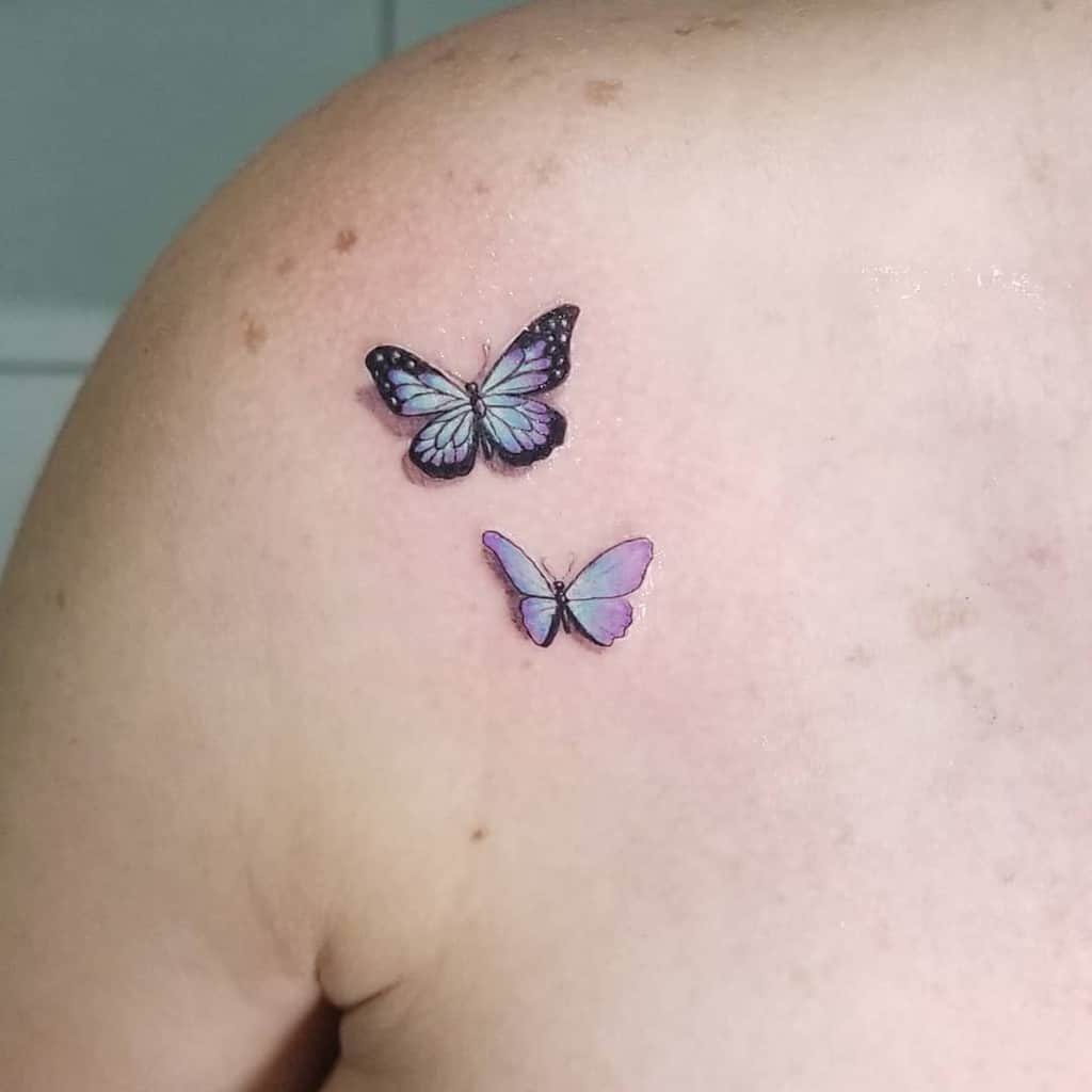 Two colorful butterfly tattoos on an upper shoulder