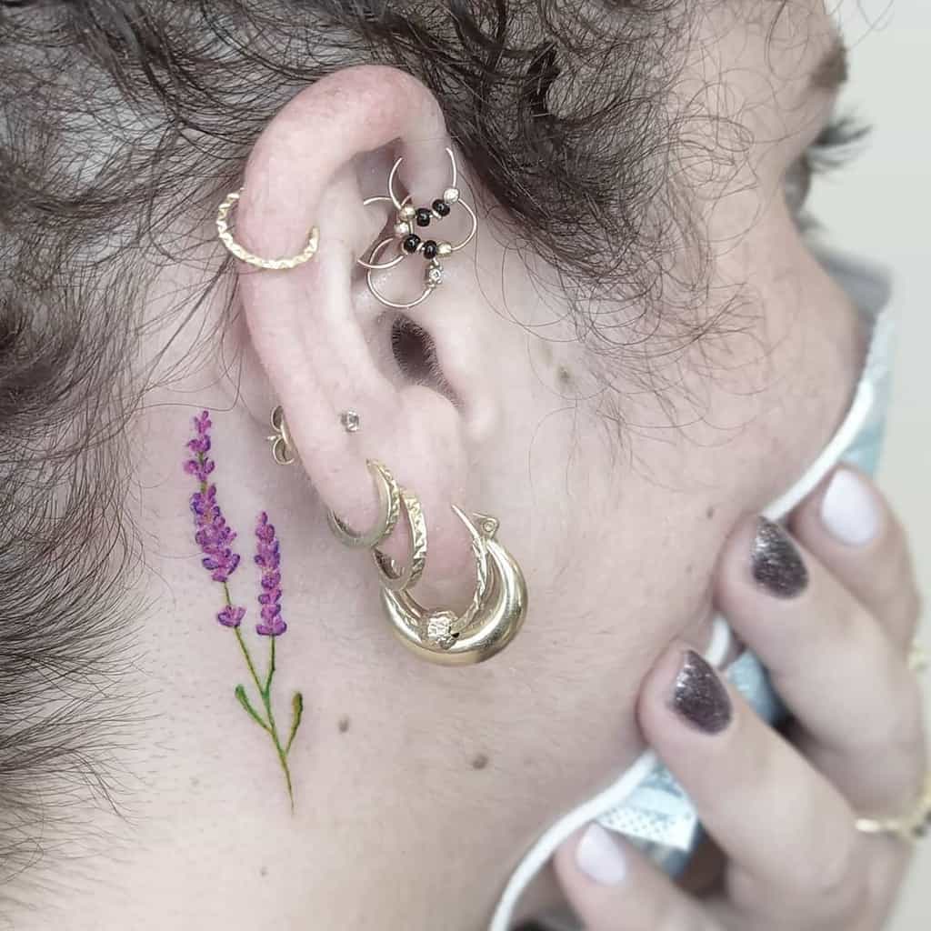 Small lavender flower tattoo behind the ear