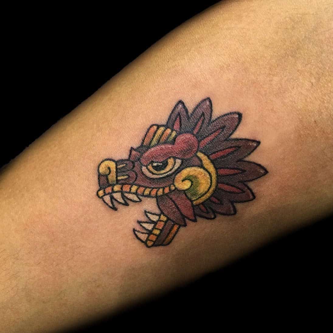 Colorful forearm tattoo of Quetzalcoatl's head with Aztec-inspired detailing