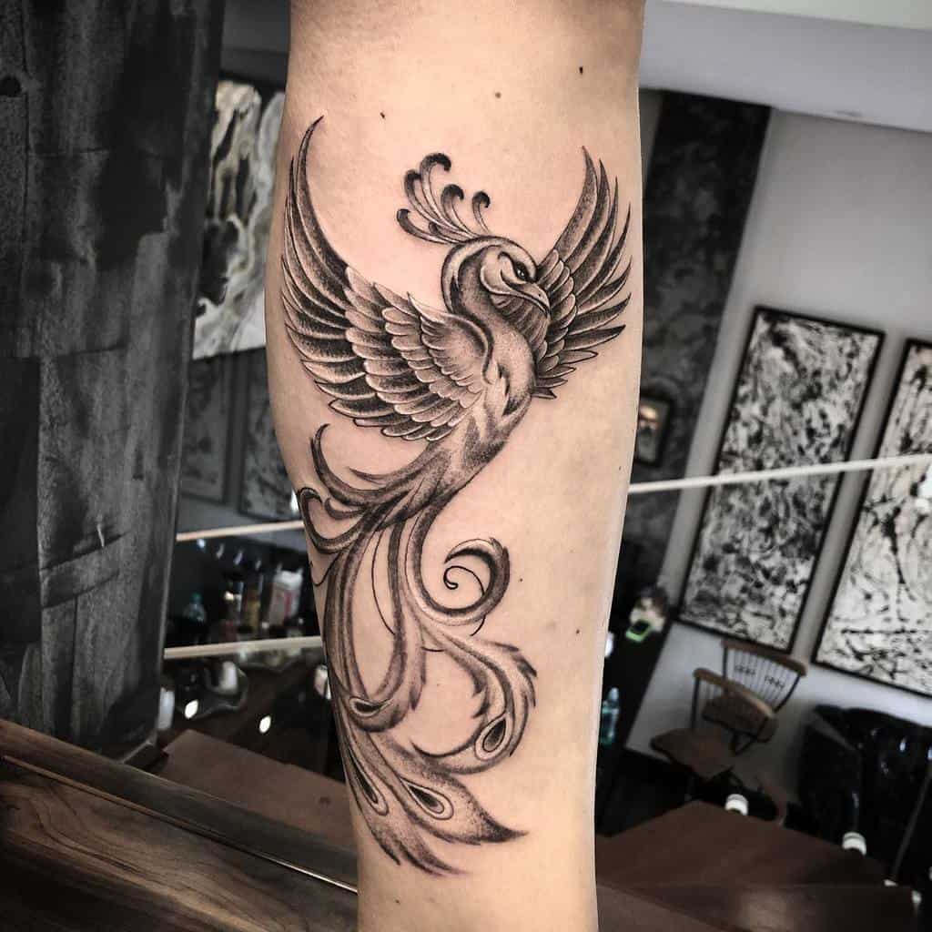 A striking black and white phoenix tattoo elegantly graces the arm