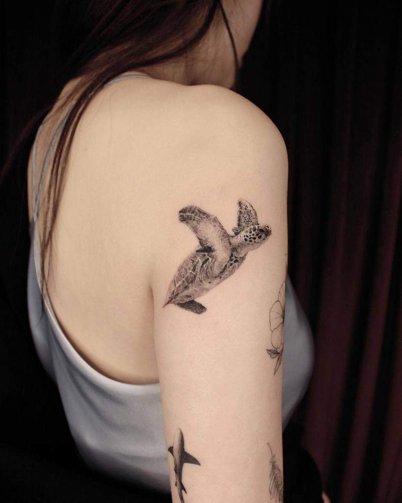 Woman with a turtle tattoo on her upper arm