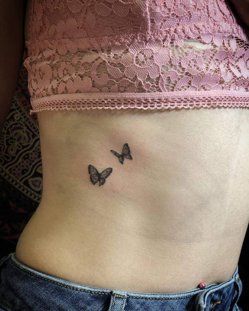 Two small butterfly tattoos on a woman's side