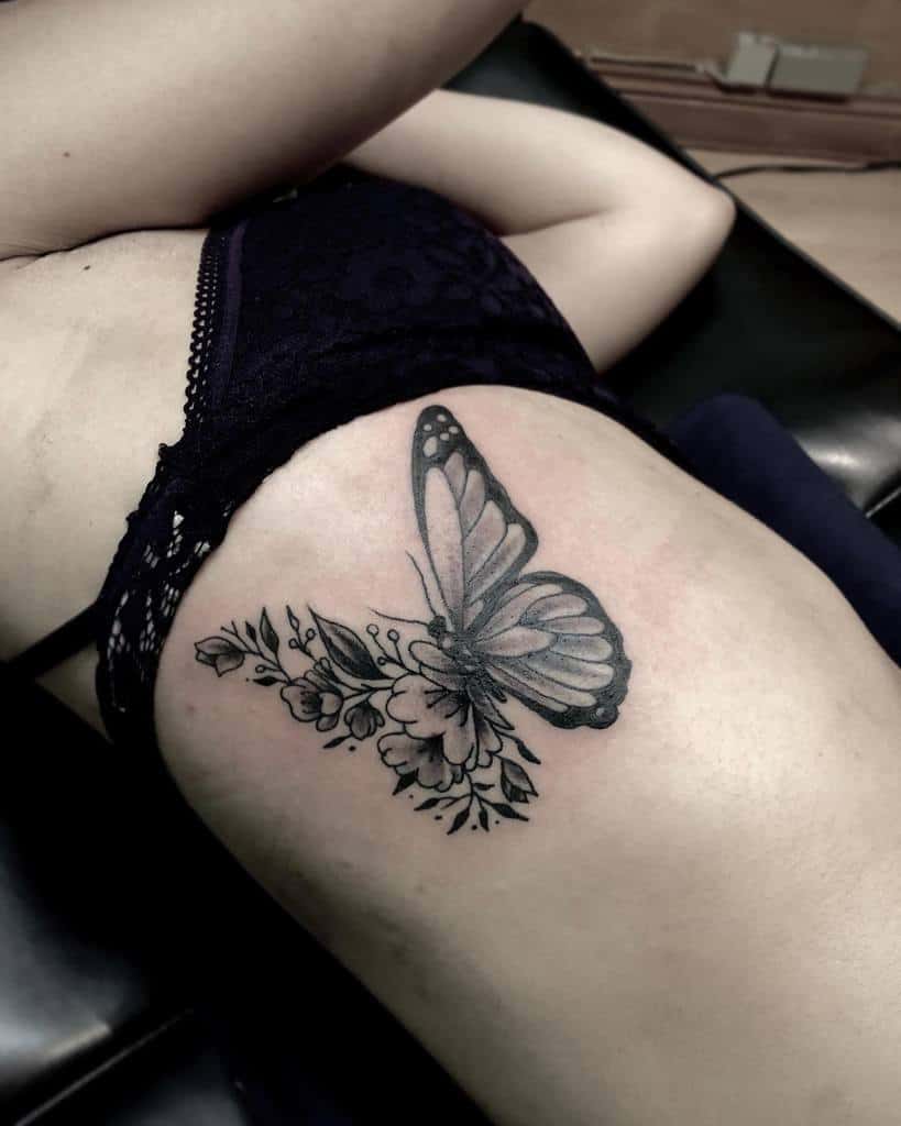 Black and gray butterfly tattoo with flowers on a woman's side