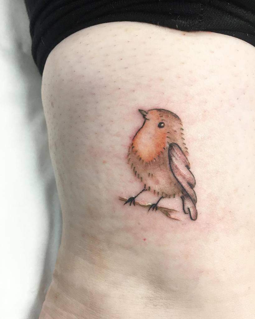 A small tattoo of a robin with orange breast and brown feathers, perched on a branch