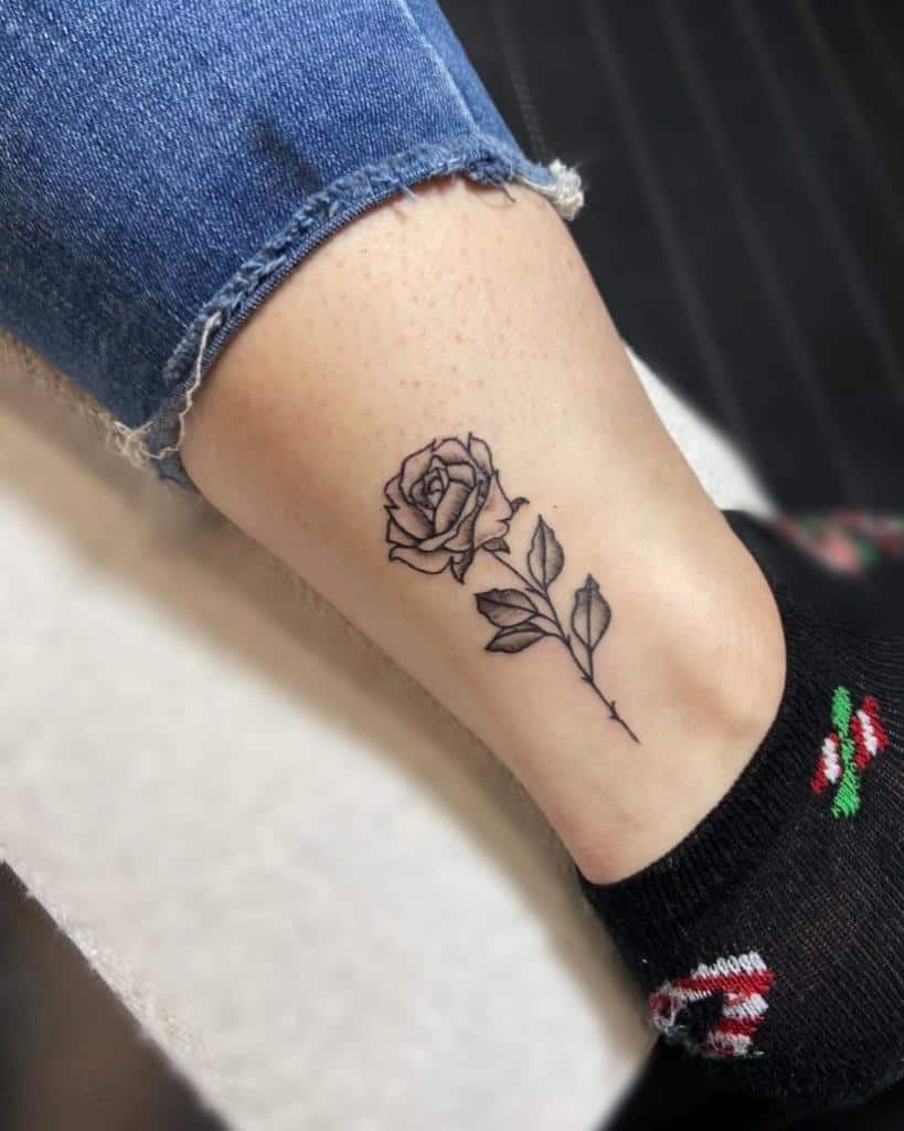 A black ink rose tattoo on the ankle