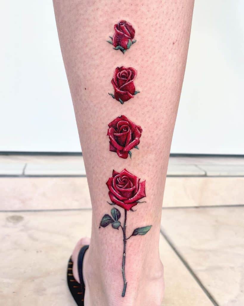 Four red roses tattooed vertically on the back of a leg, starting small at the top and becoming larger towards the bottom