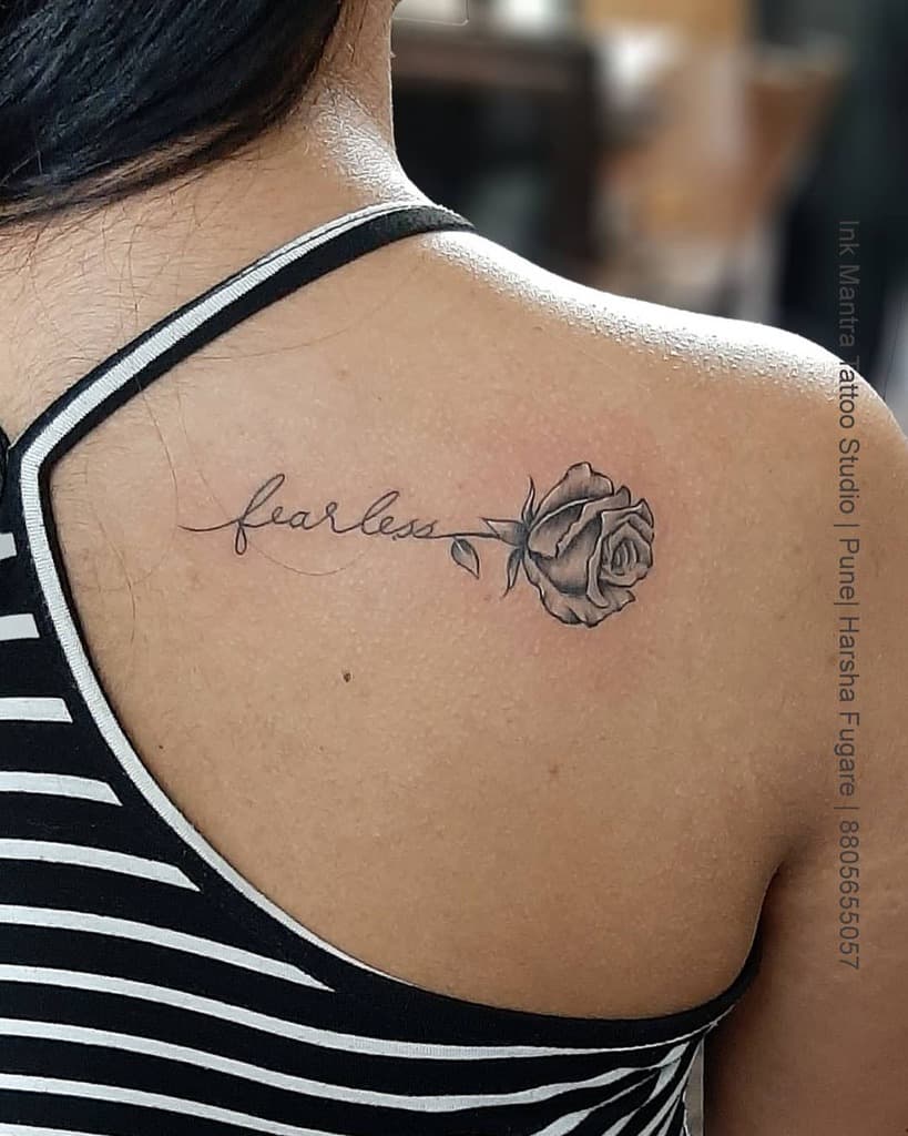 Tattoo of a rose and the word "fearless" on a woman's shoulder