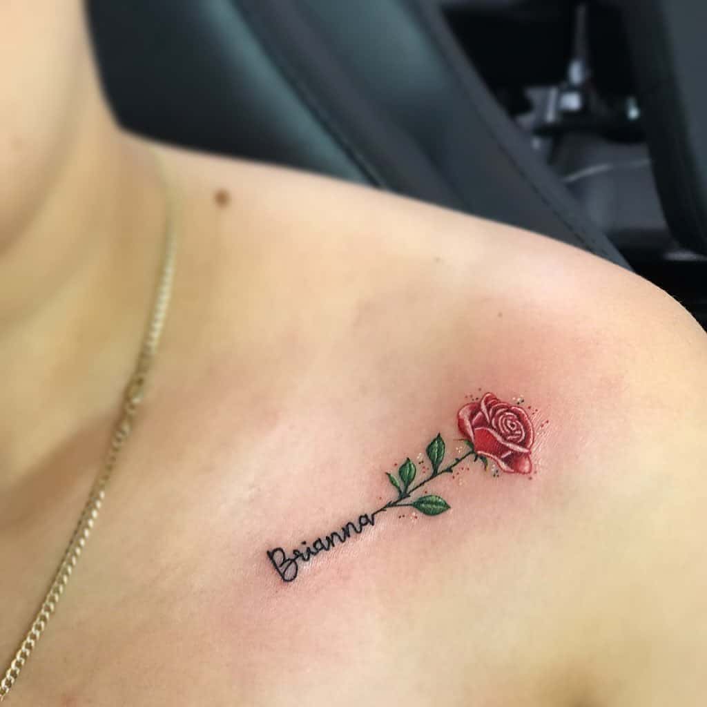 Tattoo of a red rose with green leaves and the name "Brianna" on a shoulder