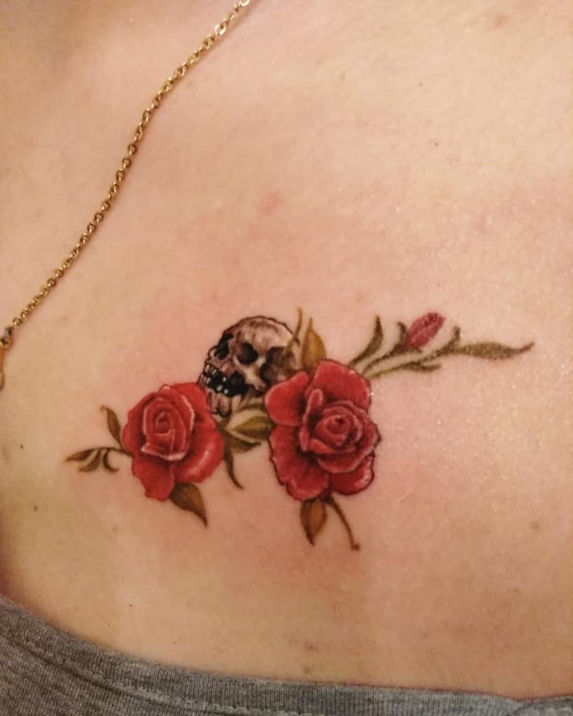 Tattoo of two red roses with a small skull in between on a shoulder