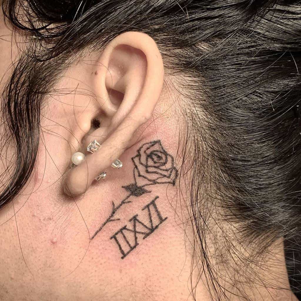 Side of a person's head with a rose tattoo and Roman numerals behind the ear