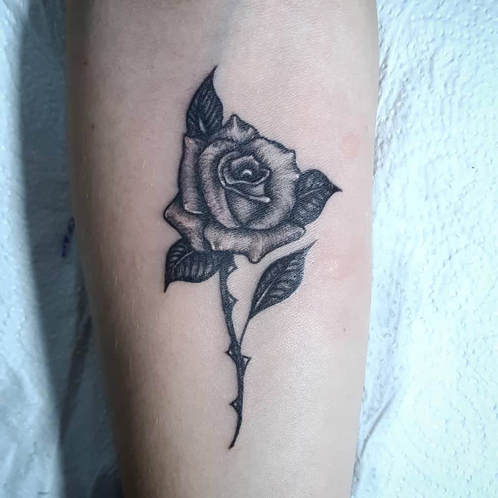 Black and gray realistic rose tattoo on a forearm