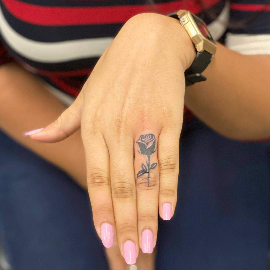 A black rose tattoo on the ring finger