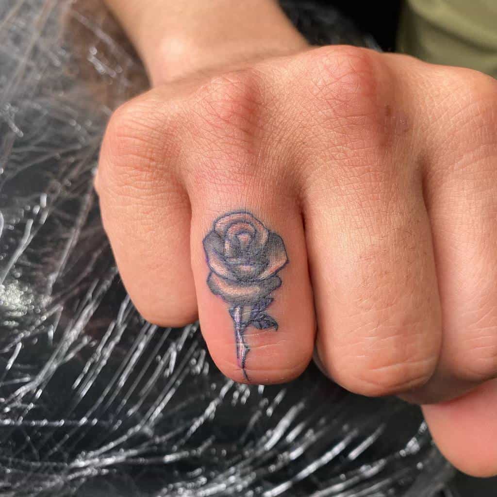 A rose tattoo on a person's finger