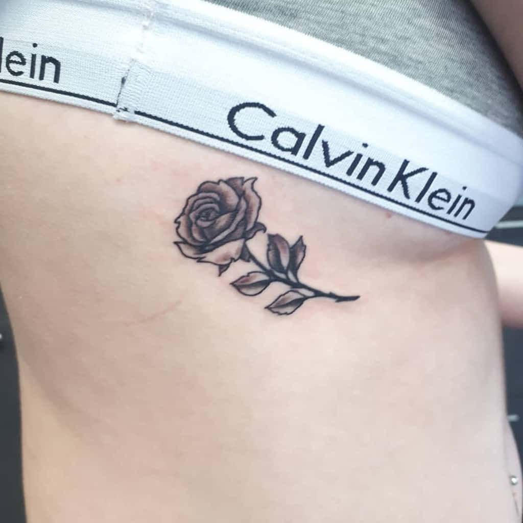 A small rose tattoo on the side of a torso