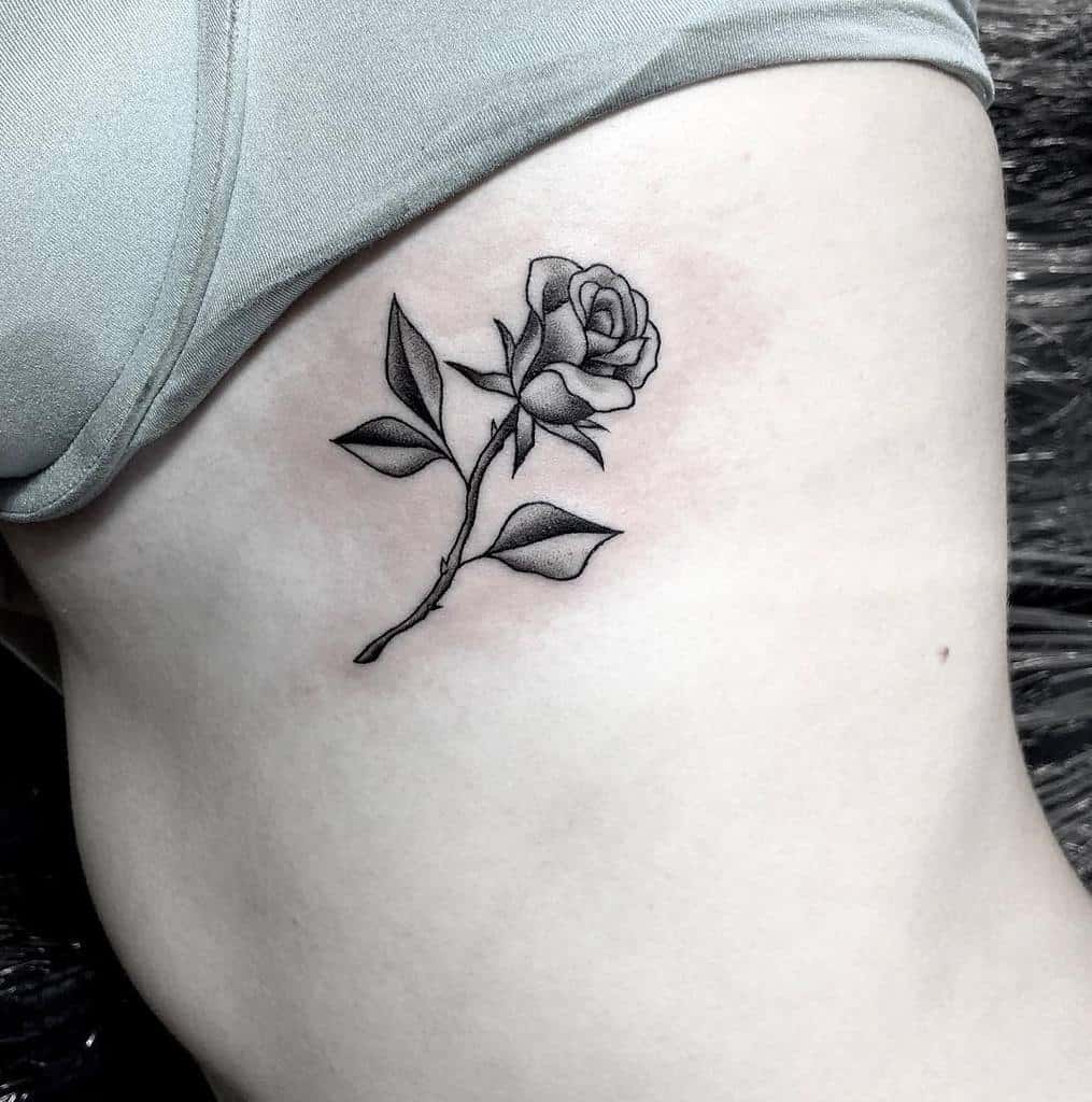 Black and gray rose tattoo on a woman's side, near the ribs