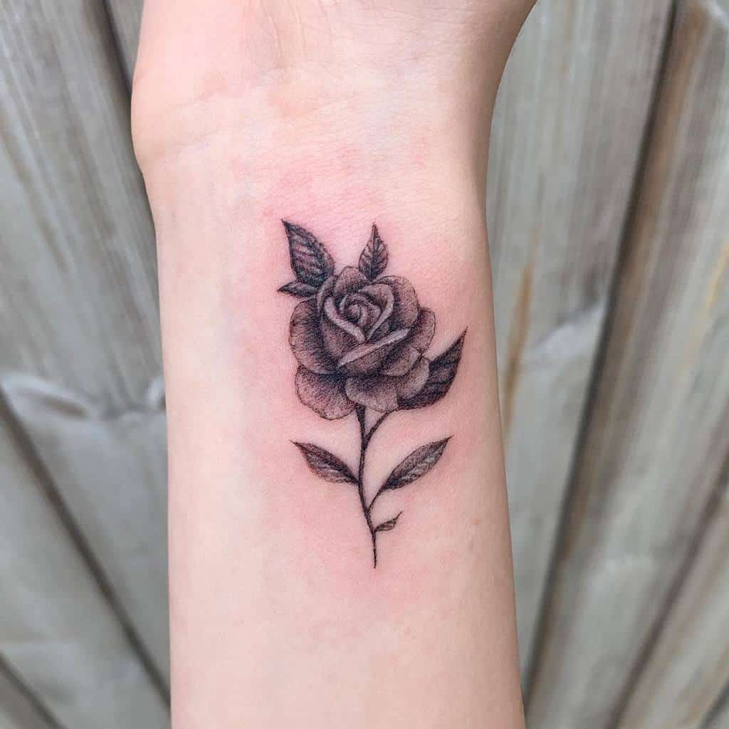 A delicate tattoo of a shaded rose on a wrist
