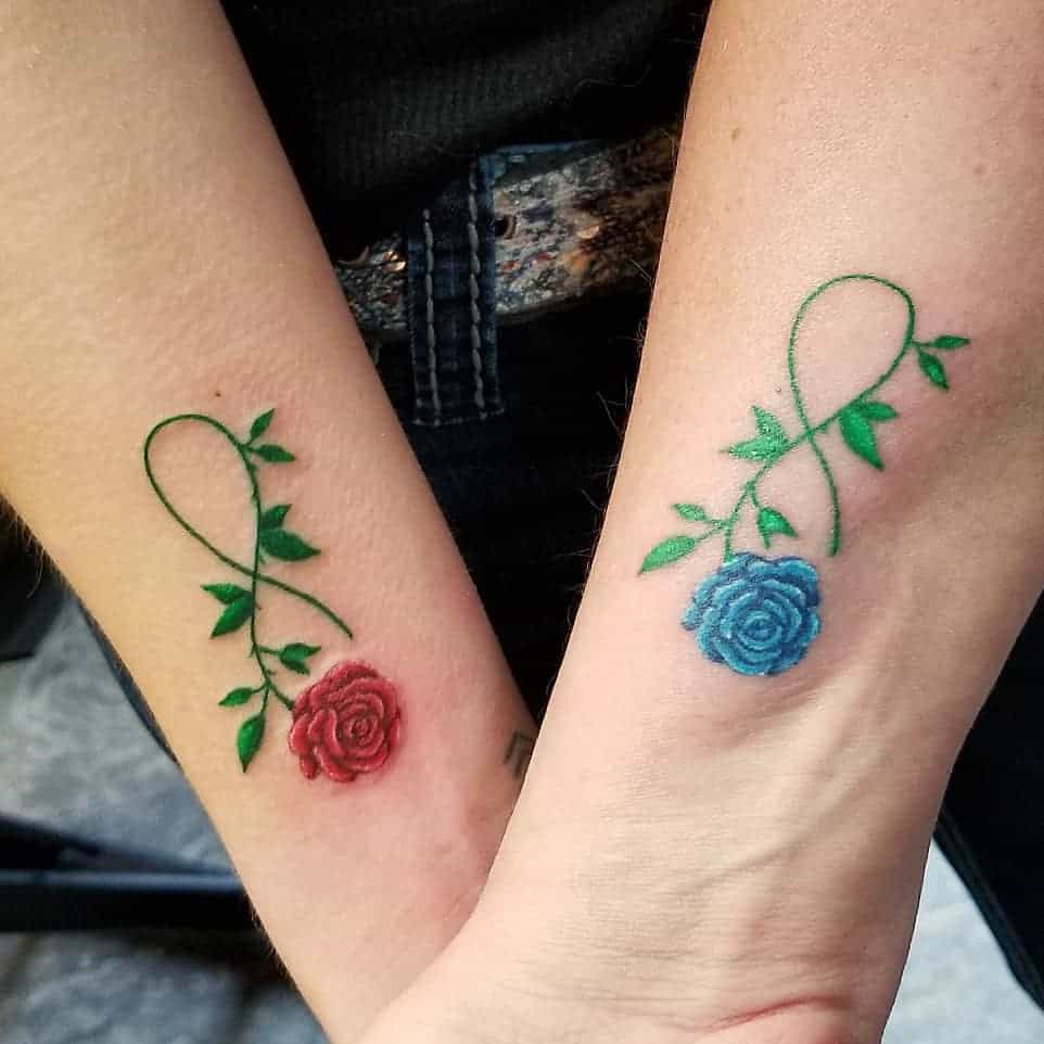 Two wrist tattoos with intertwined vines: one with a red rose, the other with a blue rose