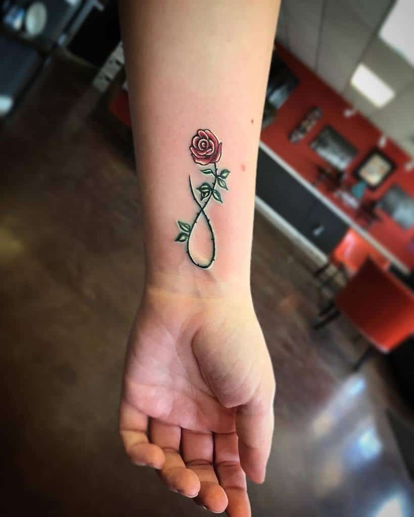 Wrist tattoo of a red rose with green stem forming an infinity symbol