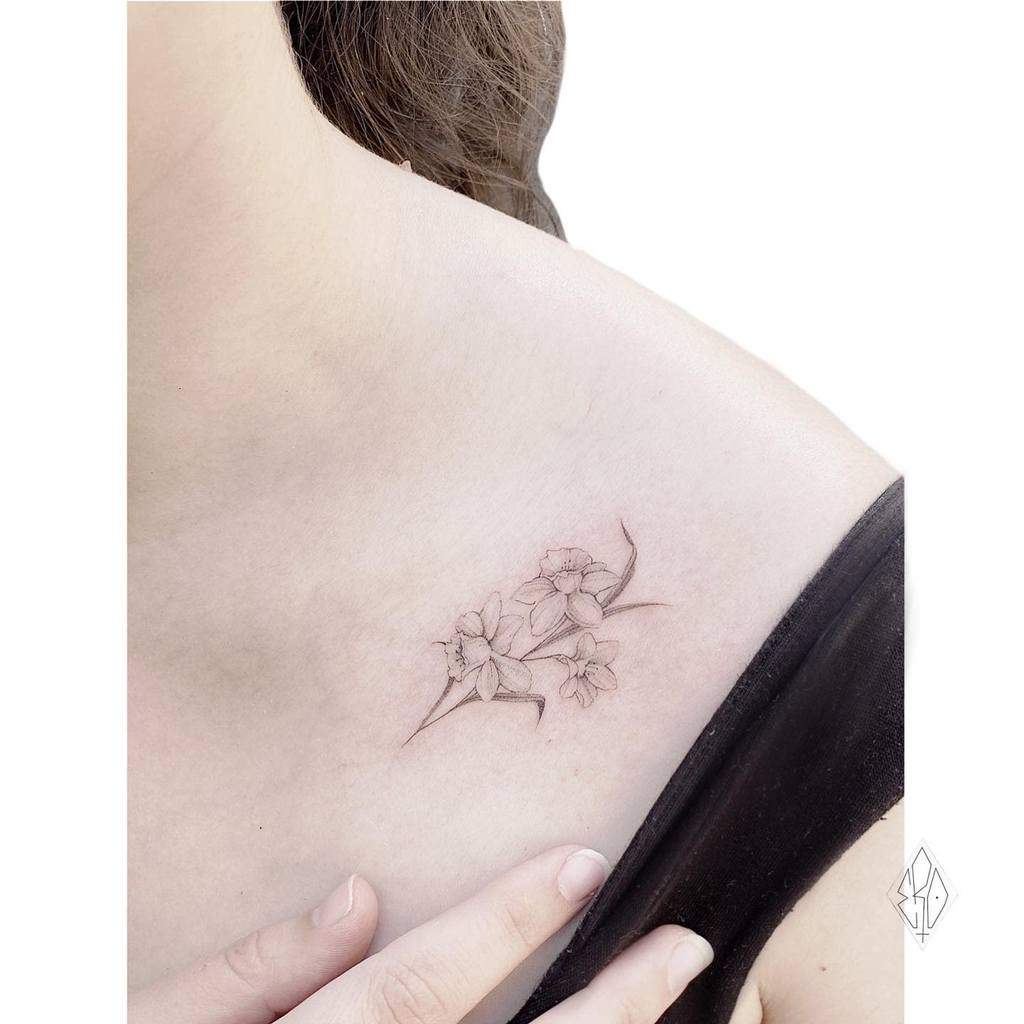 Delicate floral shoulder tattoo featuring fine-line flowers with soft shading, adding an elegant and feminine touch to the design