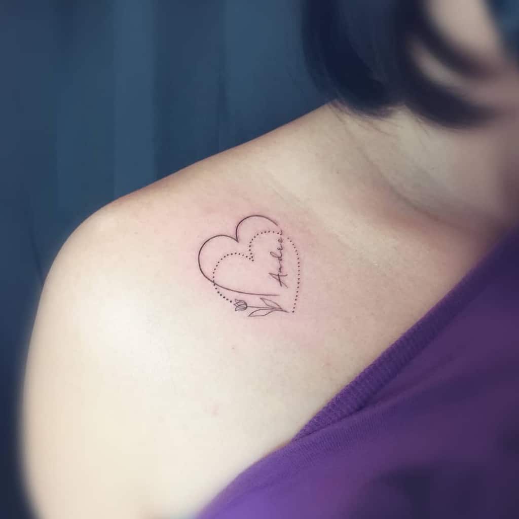 Delicate shoulder tattoo featuring an outlined heart with a dotted half, a small tulip, and a name in cursive, symbolizing love and remembrance