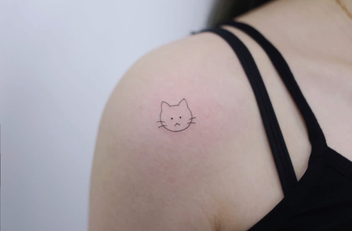 Simple cat face tattoo on an upper shoulder