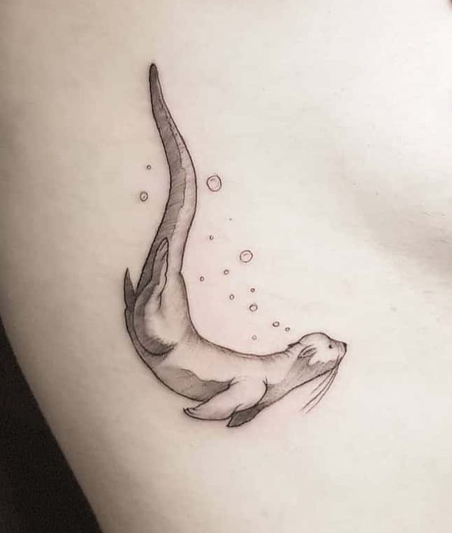 Tattoo of a playful otter swimming with bubbles, showcasing detailed shading and its long, graceful tail