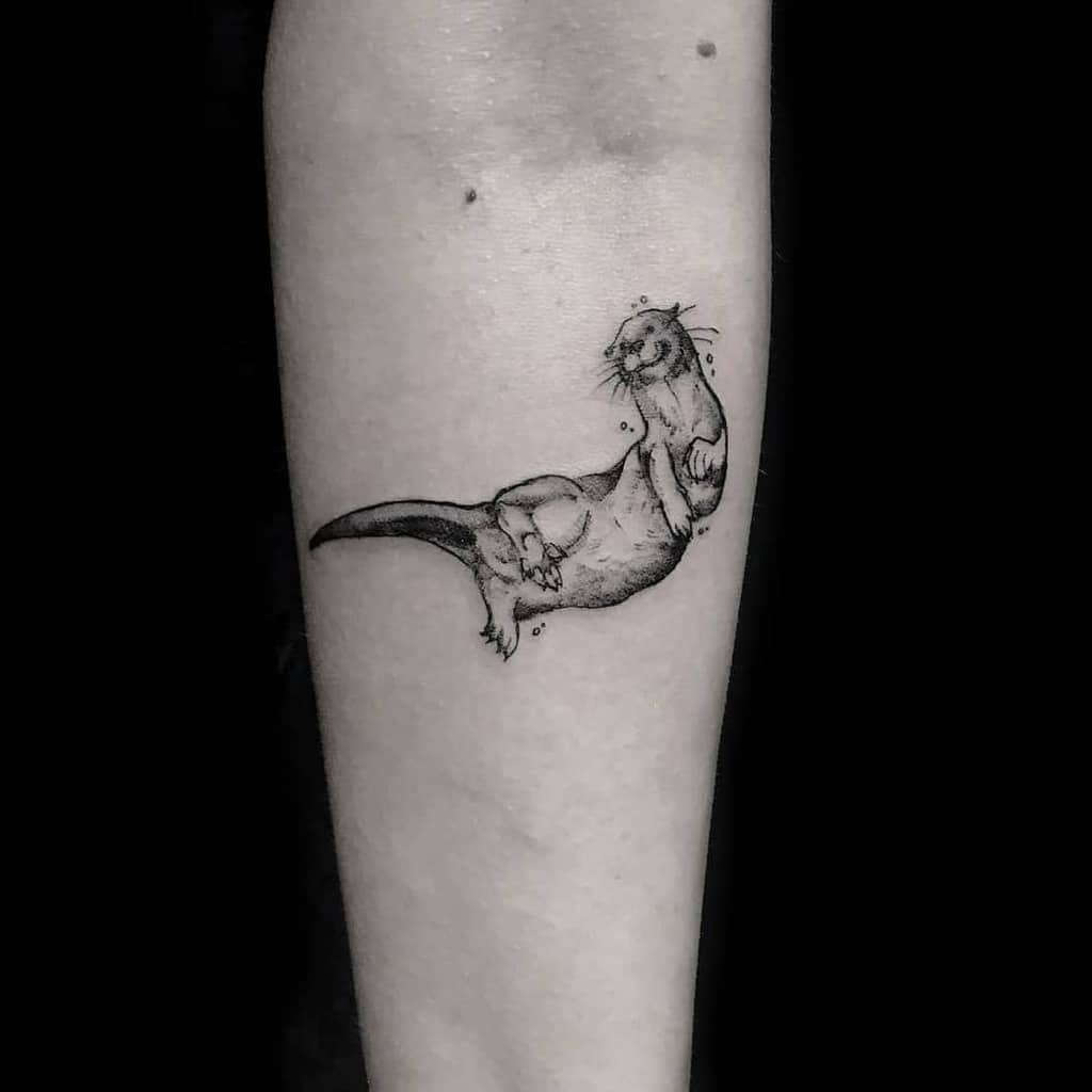 A detailed tattoo featuring an otter surrounded by bubbles graces a person's forearm
