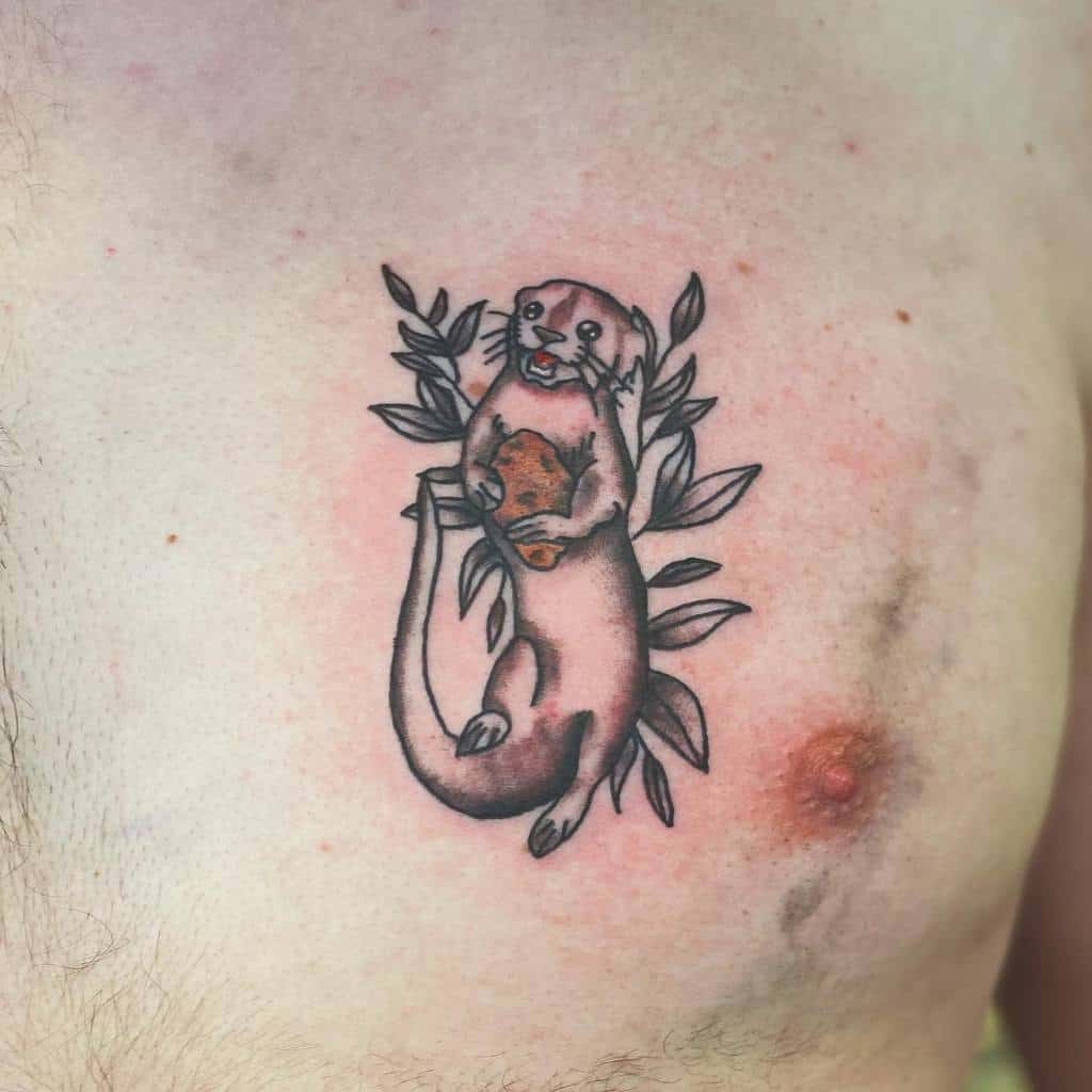 A chest tattoo featuring a lovable otter clutching a heart, nestled against vibrant leaves