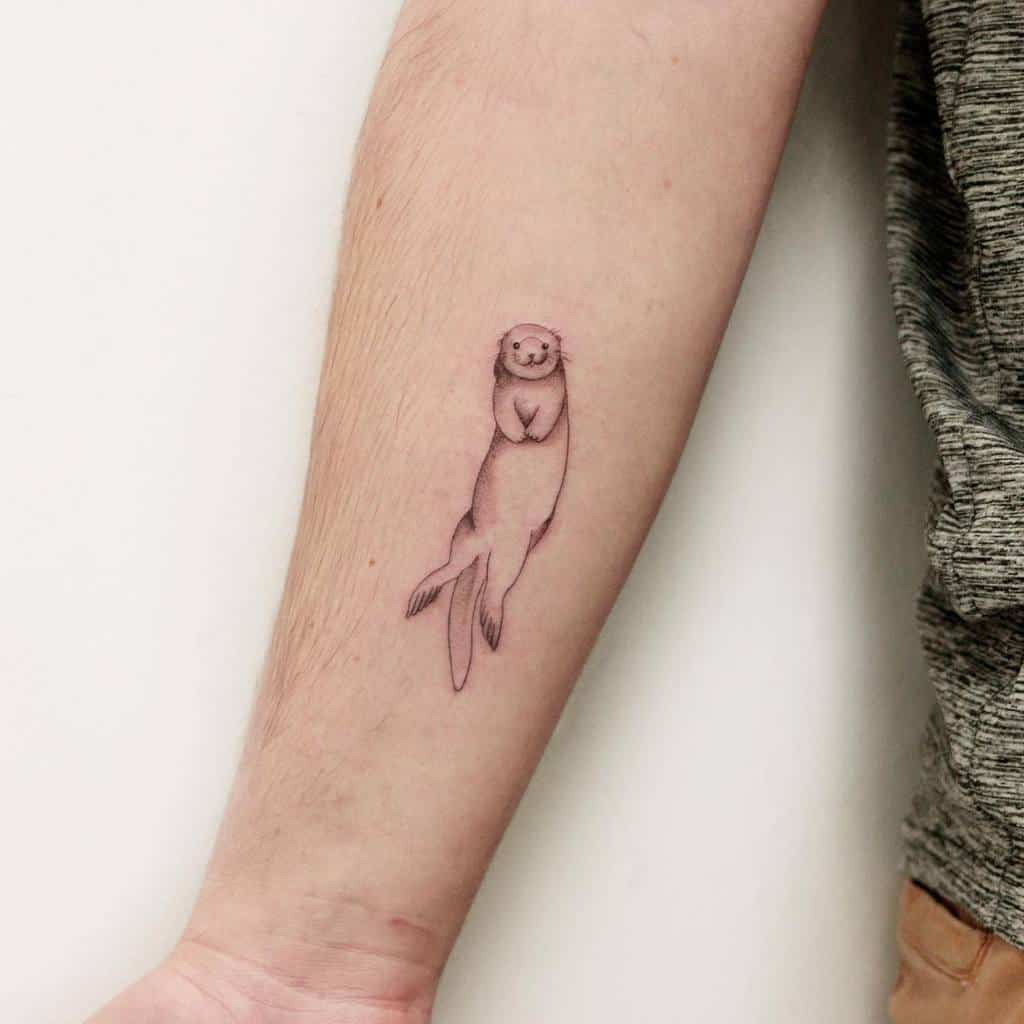 Minimalistic otter tattoo with fine linework, showcasing a relaxed and playful otter floating on its back on the forearm