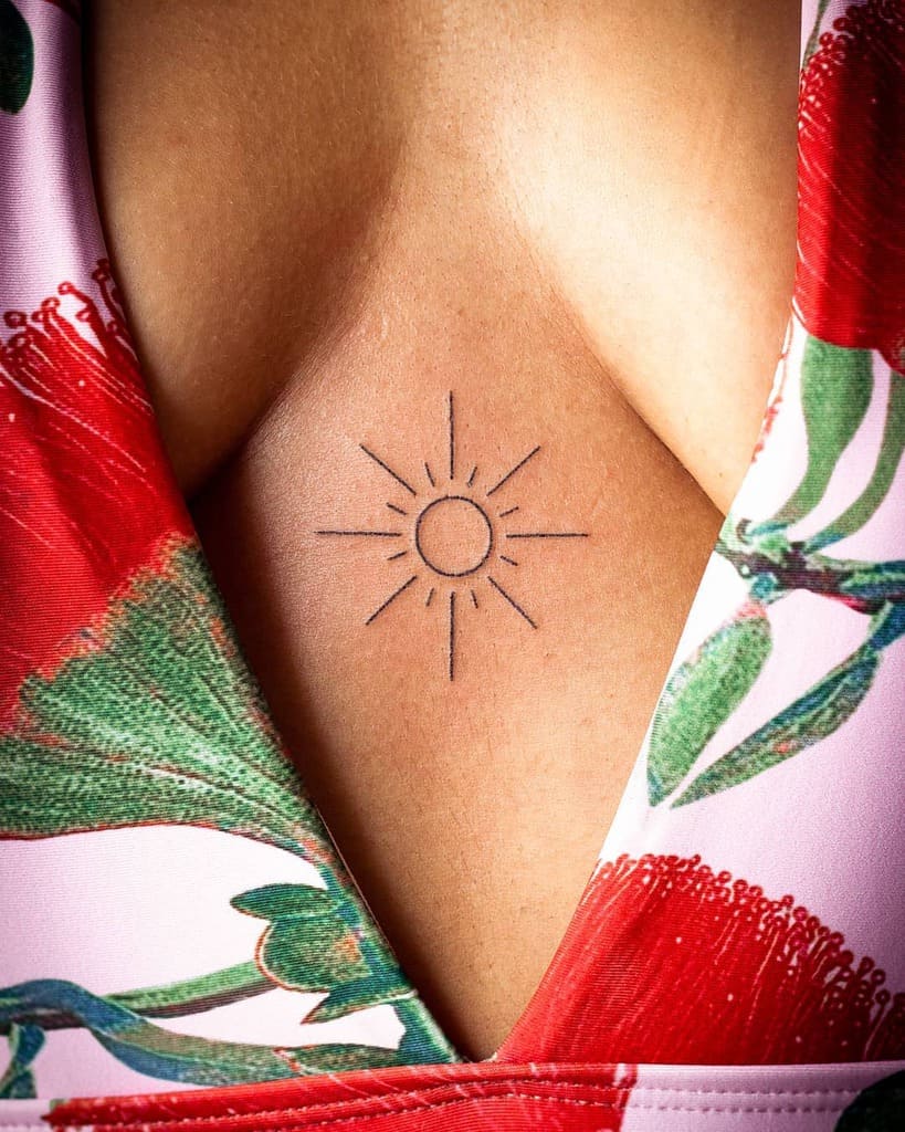 Minimalist sun tattoo with a thin circle and straight rays, placed between the chest for a delicate and elegant look
