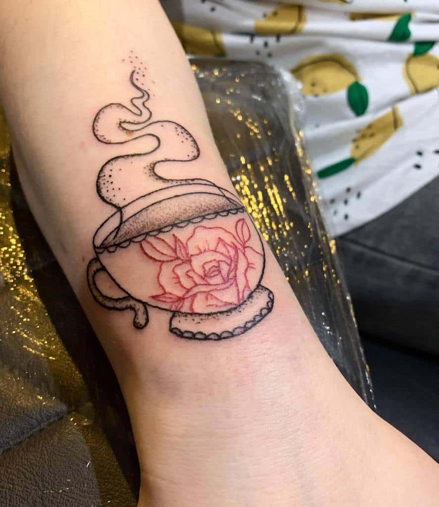 Black and red tattoo of a teacup with a rose design inside, featuring steam rising 