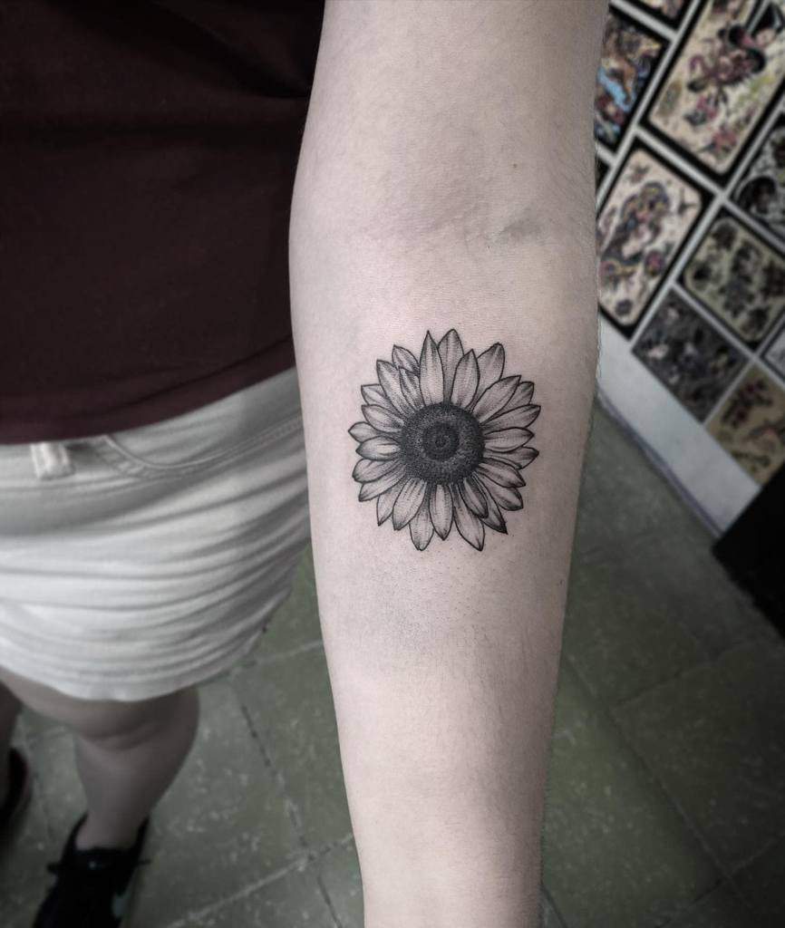 Black and grey sunflower tattoo on a forearm