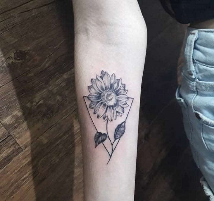 Forearm tattoo of a sunflower with leaves inside a geometric shape