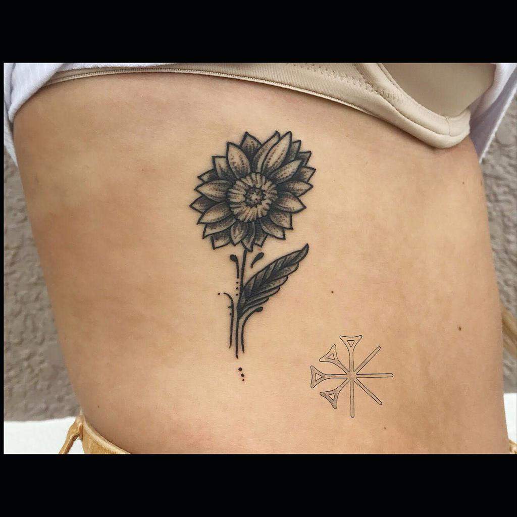 Sunflower tattoo with a geometric design on the side of a torso