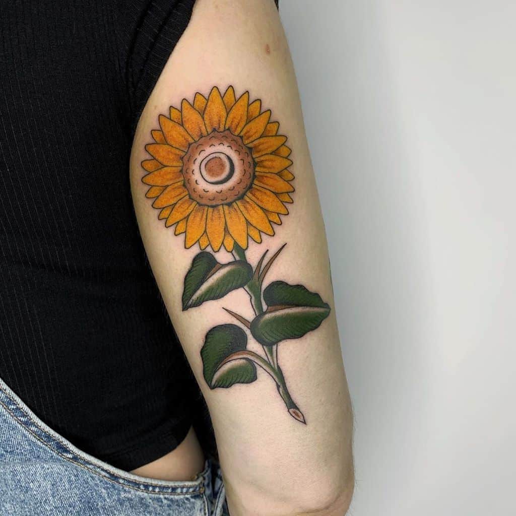 A sunflower tattoo on an arm, featuring vibrant colors and detailed leaves