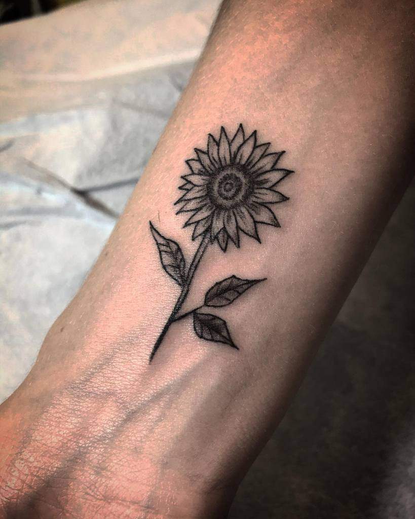 Black and white sunflower tattoo on a wrist