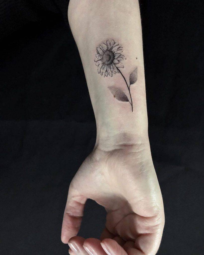 Black and grey sunflower tattoo on the inner forearm with two leaves and shading details