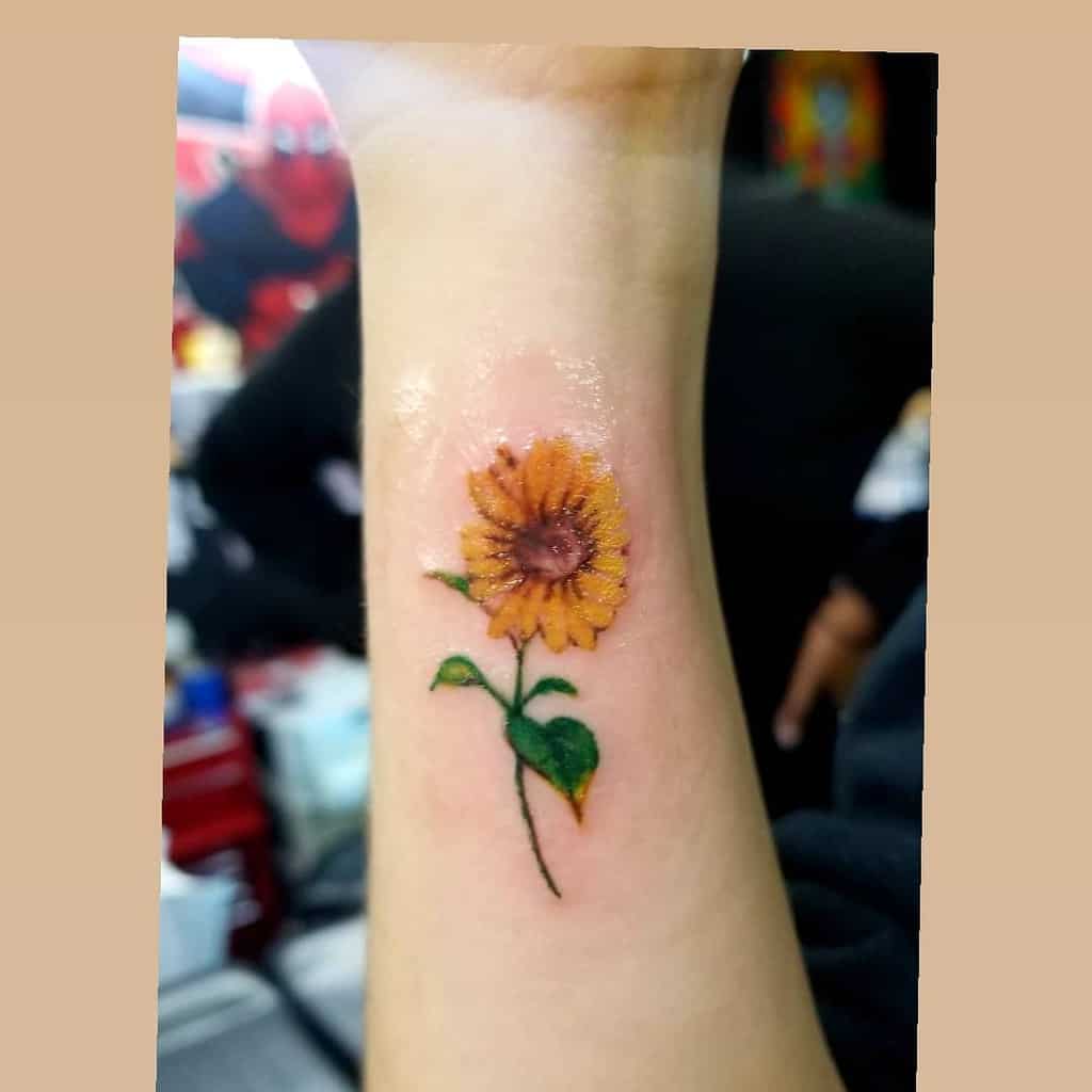 A small sunflower tattoo on a wrist