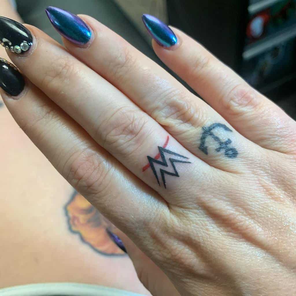 Hand with nautical and wave tattoos on fingers