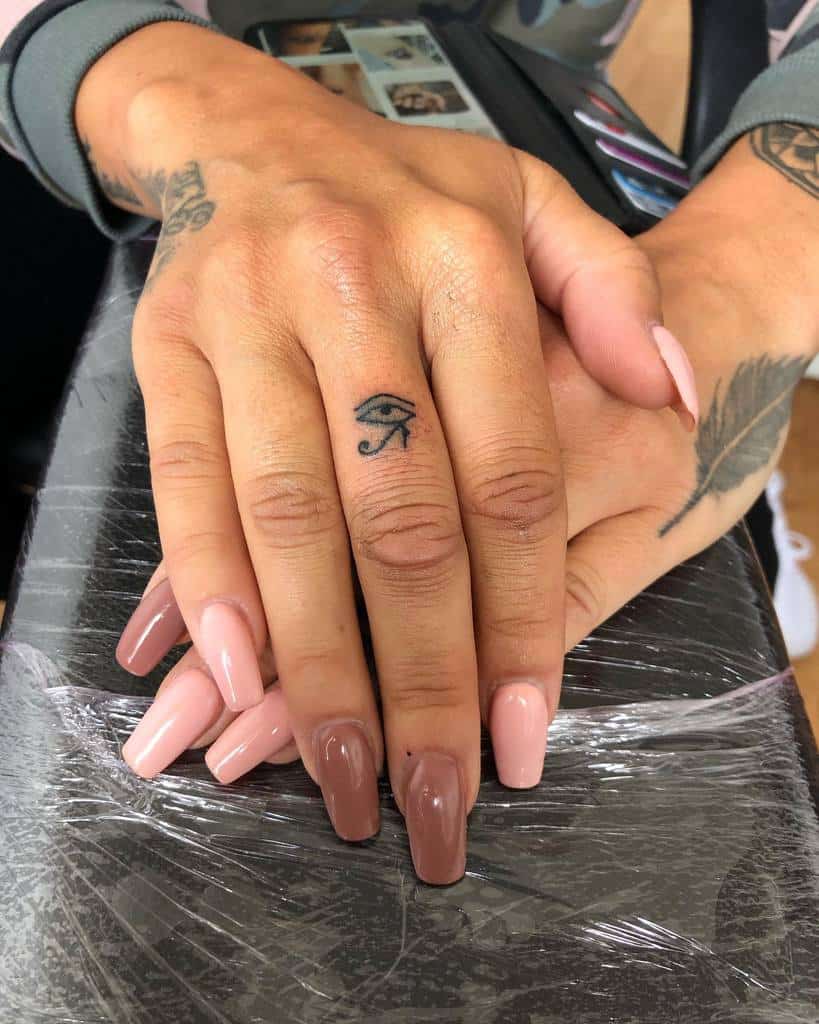 Simple Eye of Horus tattoo on the finger, symbolizing protection, power, and health